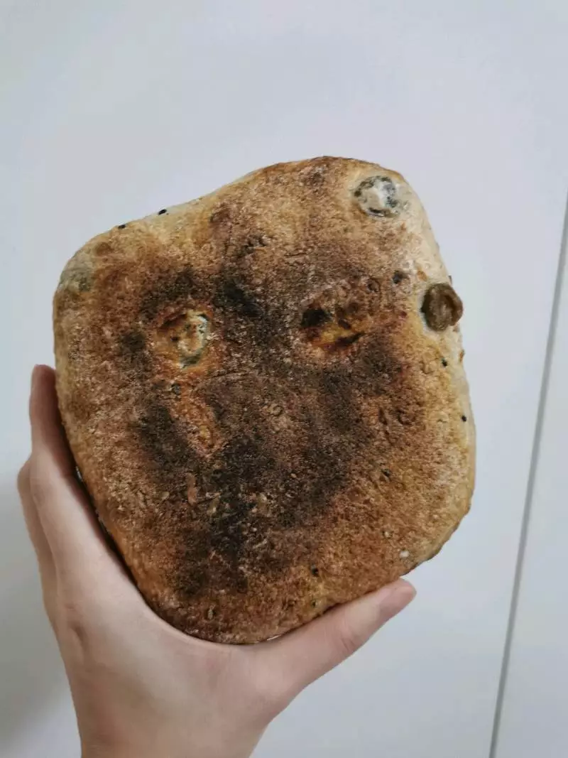 Hand holding a well-risen loaf of bread baked on a Steel Craft baking steel